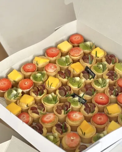 Mini fruit tarts topped with fresh seasonal fruits in golden tart shells