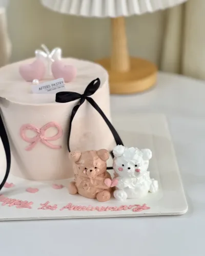 Bear-themed anniversary cake with cute couple topper and pastel decorations