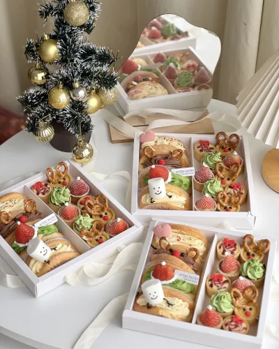 Christmas gift box filled with festive cakes, cookies, and chocolates